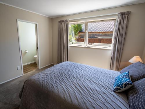 a bedroom with a bed and a large window at At The Beach - Pohara Holiday Home in Takaka