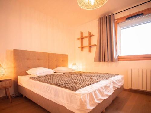 ein Schlafzimmer mit einem großen Bett mit Fenster in der Unterkunft Charmant T2 à Valmorel avec parking et casier à ski - FR-1-291-1016 in Valmorel