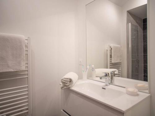 ein weißes Badezimmer mit Waschbecken und Spiegel in der Unterkunft Bel appartement 5 pièces à Valmorel avec parking, 8 pers. - FR-1-291-1018 in Valmorel