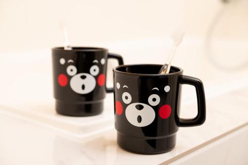 two black coffee mugs with hello kitty faces on them at KAMENOI HOTEL Aso in Aso