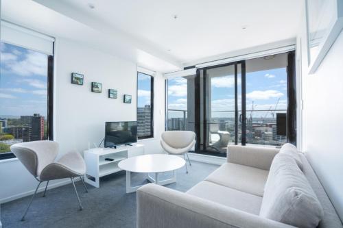 a living room with white furniture and large windows at Amazing Skytower View 2 Bedroom 2 bathroom Apartment in Auckland