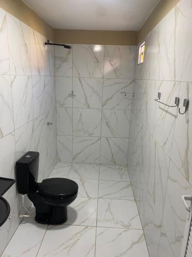 a bathroom with a black toilet and a shower at Portal do Sol in Canoa Quebrada