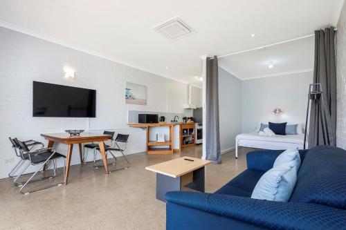 a living room with a blue couch and a table at Windsurfer Beach Chalet 3 in Lancelin