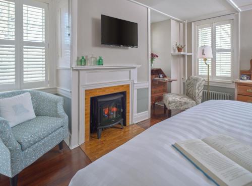 a bedroom with a fireplace and a bed and a tv at Old Manse Inn in Brewster