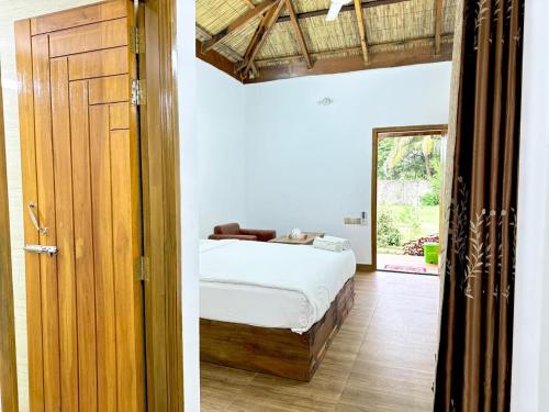 a bedroom with a bed and a wooden door at Angel Eco Resort, Cox Bazar in Dhoāpālong