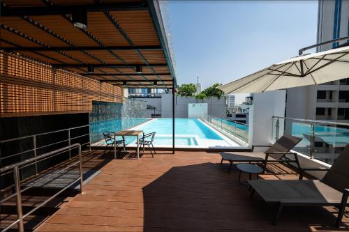 a balcony with a pool and tables and an umbrella at 6th Avenue Sukhumvit 305 BTS Asoke & Nana MRT Sukhumvit in Bang Kapi