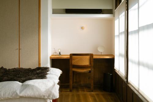 a bedroom with a desk with a chair and a bed at Une stay&diner in Sasayama