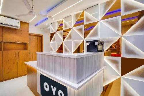 a lobby with a wall of shelves and a tv at Hotel O Heaven in Gwalior