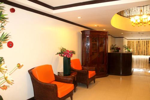 a waiting room with orange chairs and a podium at Paradise Garden Hotel and Convention Center Boracay Powered by ASTON in Boracay