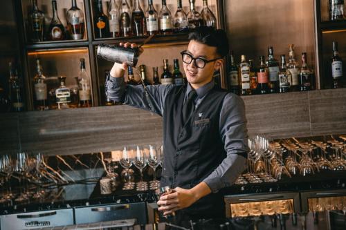 a man is standing behind a bar with a bottle of alcohol at JW Marriott Hotel Hanoi in Hanoi