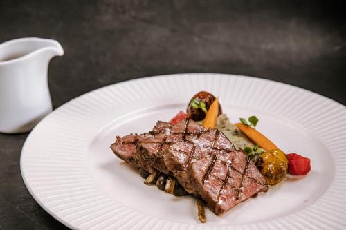 a white plate with a piece of meat and vegetables at JW Marriott Hotel Hanoi in Hanoi