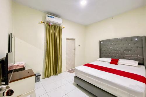 Un dormitorio con una cama grande y un televisor. en RedDoorz Syariah at RPCC Rantauprapat, en Rantauprapat