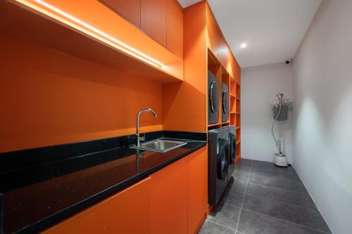 eine Küche mit orangefarbenen Wänden und einem Waschbecken in der Unterkunft Banana Fun Hotel Ergong Subway Station Branch in Guangzhou