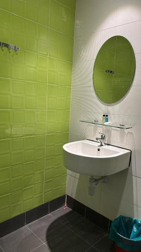 a green bathroom with a sink and a mirror at Mizie Hotel Kuala Lumpur in Kuala Lumpur