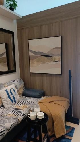 a room with a bed and a table with cups on it at Cozy New 1BR Fame Residences Condo with Balcony in Manila