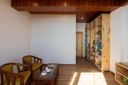a room with a table and chairs and a book shelf at StayVista at DAAFI House with Comp Breakfast in Theog