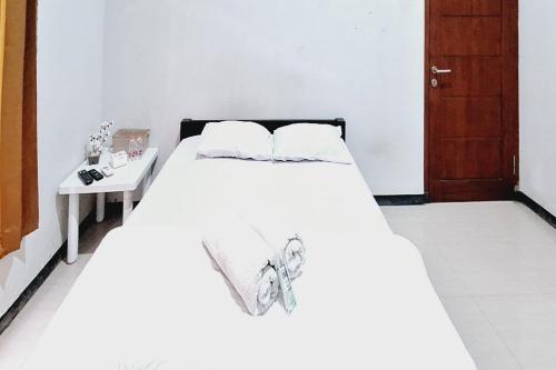 a white bed in a room with a table at HKP Homestay RedPartner Blitar in Blitar