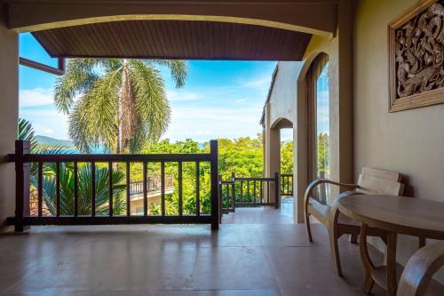 a room with a table and a balcony with a palm tree at Ocean Pearl Seaview Residence in Rawai Beach