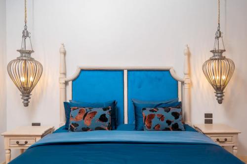 a bedroom with a blue bed with two lights at Ocean Pearl Seaview Residence in Rawai Beach
