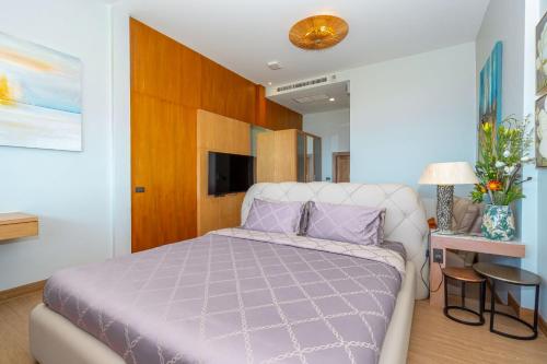 a bedroom with a king sized bed with purple pillows at Ocean Pearl Seaview Residence in Rawai Beach
