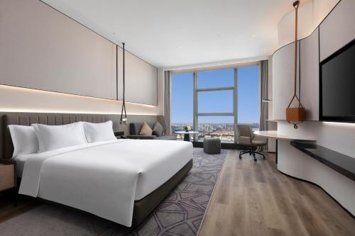 a hotel room with a large white bed and a desk at Crowne Plaza Taizhou City Center by IHG in Taizhou