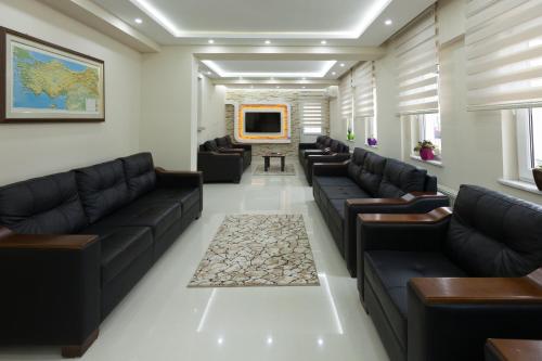 a waiting room with black leather couches and a tv at Gizem Pansiyon in Canakkale