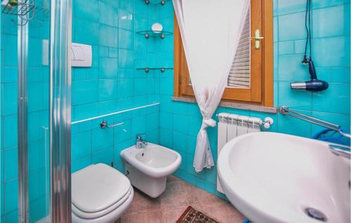 a blue bathroom with a toilet and a sink at 2 Bedroom Cozy Home In Sabaudia in Sabaudia