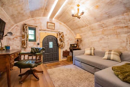 a living room with a couch and a table and a desk at The Hobbit House in Edenfield