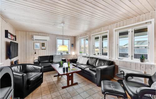 a living room with black leather furniture and windows at Holiday Home Arvidvej Hvide Sande Xii in Bjerregård