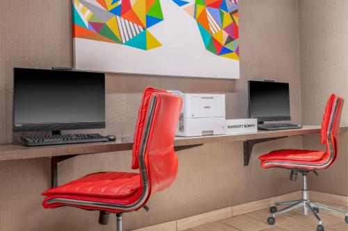 two red chairs in front of desks with computers at Courtyard St. Louis Downtown/Convention Center in Saint Louis