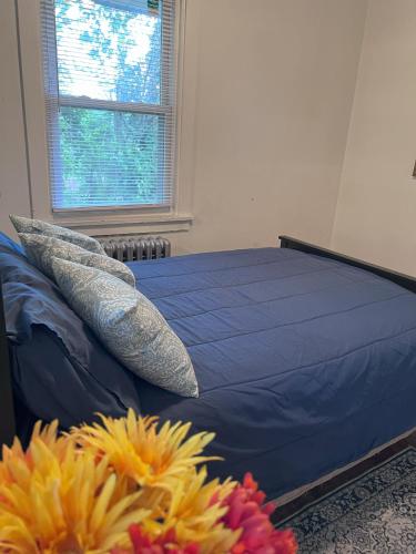 a bed with blue sheets and pillows next to a window at Charming 3 Bedroom Cottage Apartment in a Tudor-Style Home in Pittsburgh