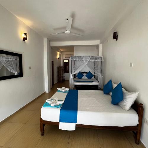a bedroom with a bed with blue and white pillows at PRANA Beach Hotel Hikkaduwa in Hikkaduwa