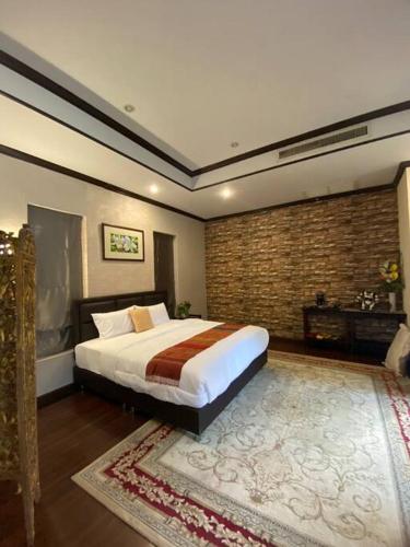 a bedroom with a large bed and a brick wall at Vela House Phuket in Changwat Phuket