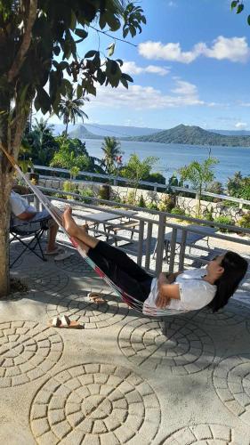 a woman laying on a hammock on the beach at Villa with Private Pool Overlooking Taal Lake in Kinalaglagan