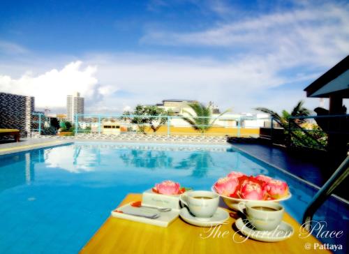 una mesa con dos tazas y un bol de fruta junto a una piscina en The Garden Place Pattaya en Pattaya centro