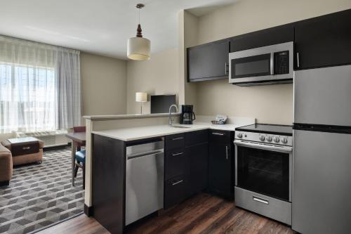 a kitchen with black and white appliances and a living room at TownePlace Suites by Marriott Lafayette South in Lafayette