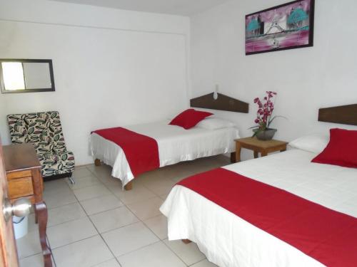a hotel room with two beds and a chair at Hotel Oasis Cuyutlan in Cuyutlán