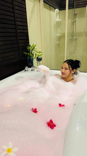 a woman in a bath tub with flowers on it at Vela House Phuket in Changwat Phuket