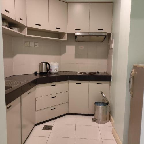 a kitchen with white cabinets and a trash can at Song Service Apartment formerly known as Jinhold Service Apartment in Kuching