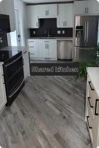 a kitchen with white cabinets and stainless steel appliances at Cozy in Regina