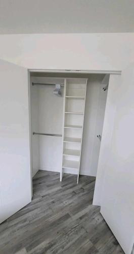 an empty room with a white desk and shelves at Cozy in Regina