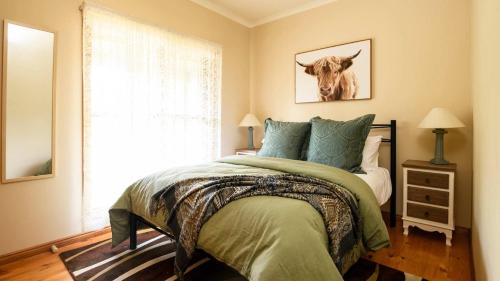 a bedroom with a bed with a cow picture on the wall at Honeycomb Lodge in Daylesford
