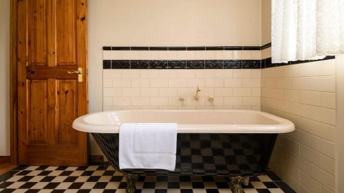 a bath tub in a bathroom with a checkered floor at Honeycomb Lodge in Daylesford
