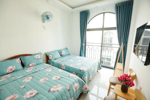 a bedroom with two beds and a large window at Villa Homestay Sumo in Vung Tau