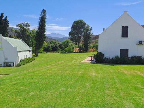 a large grass field next to a white house at Red Ridge Mountain Lodge in Buffelskloof