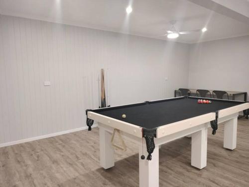 a ping pong table in an empty room with a pool at Private Bush & Beach Retreat in Eudlo
