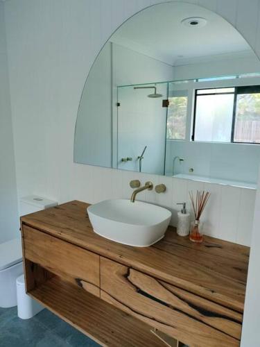a bathroom with a sink and a mirror at Private Bush & Beach Retreat in Eudlo