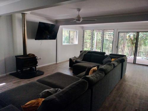 a living room with a couch and a tv at Private Bush & Beach Retreat in Eudlo