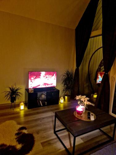 a living room with a tv and a couch and a table at Atpūtas Comfort Cabin House in Kalngale