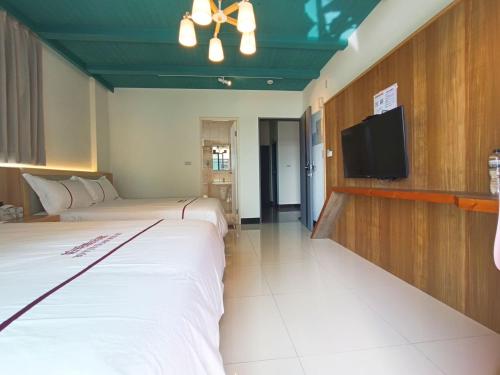 a hotel room with two beds and a flat screen tv at 鉑玥館民宿 in Jinning